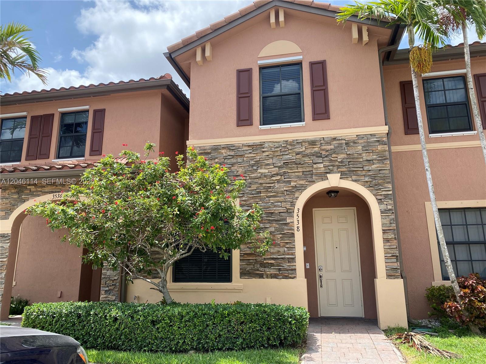 A two-story townhouse exterior features tan stucco walls, stone veneer accents, and a tiled roof — 3538 W 88th Terrace # 3538, Hialeah Gardens FL 33018, HIALEAH GARDENS, FL