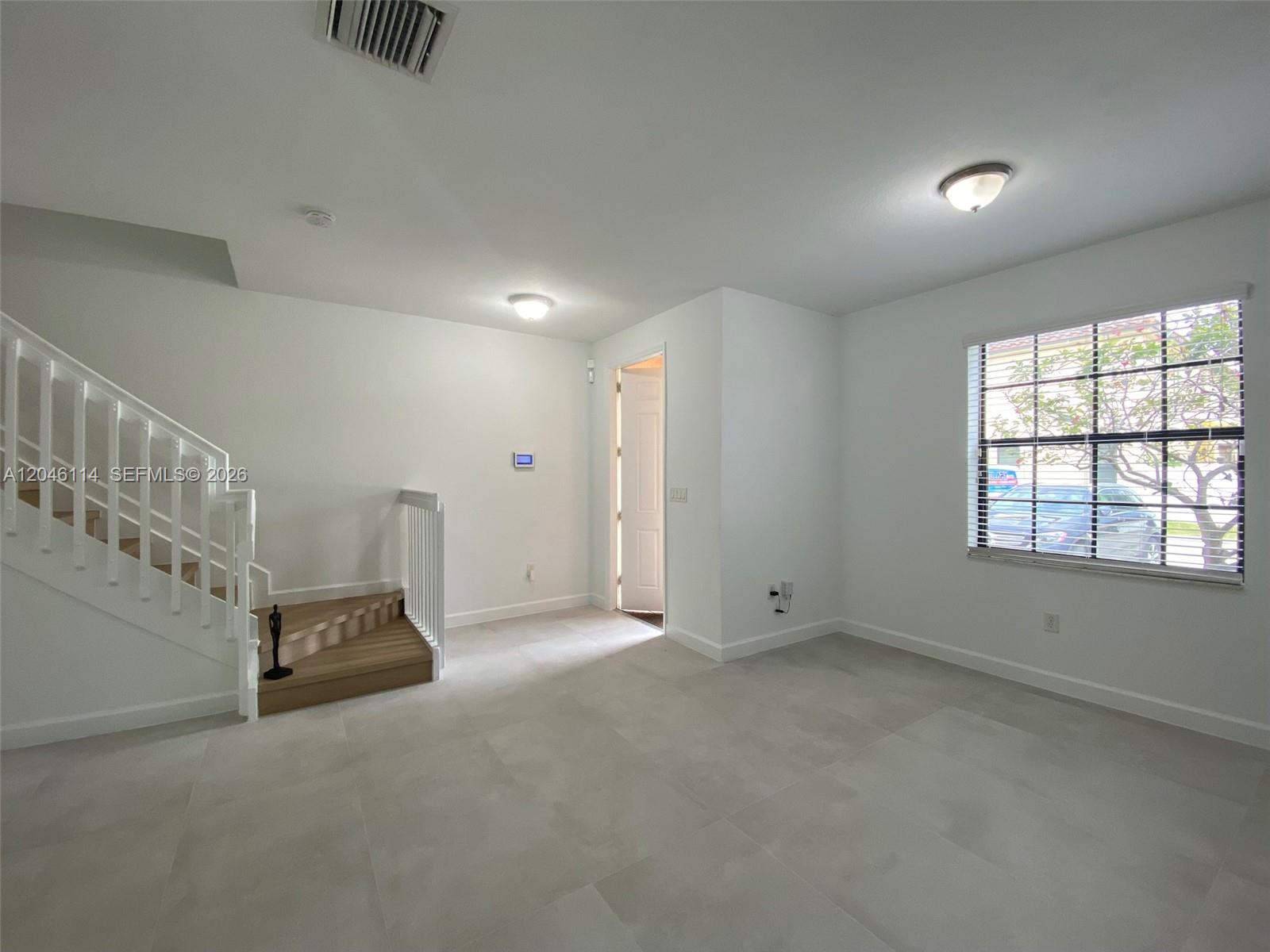 A bright room features light tile flooring, a white staircase, and a large window — 3538 W 88th Terrace # 3538, Hialeah Gardens FL 33018, HIALEAH GARDENS, FL
