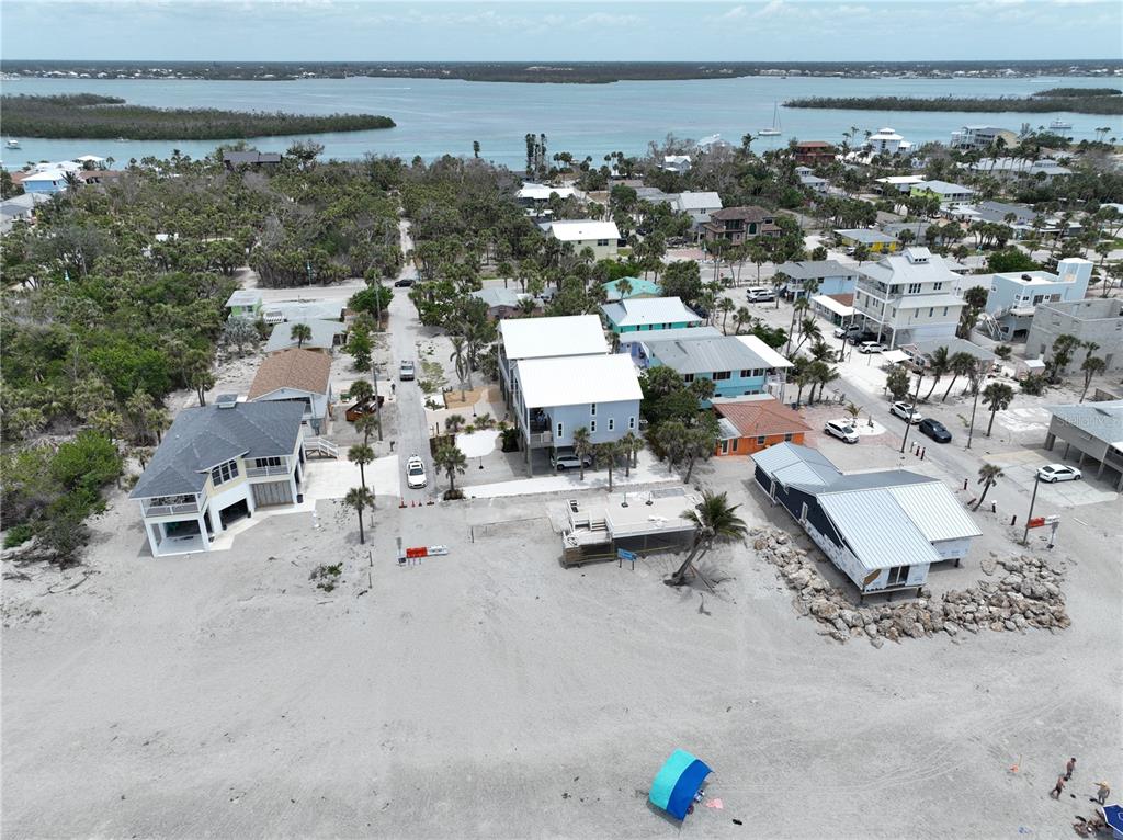 An aerial view shows several coastal houses situated along a sandy beach near the water — 45 COQUINA LANE, ENGLEWOOD, FL