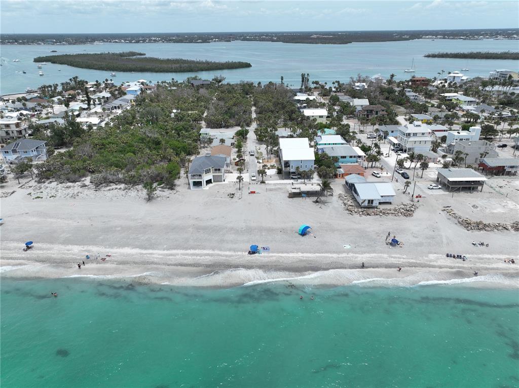 An aerial view shows beachfront houses along a sandy shore with turquoise water — 45 COQUINA LANE, ENGLEWOOD, FL