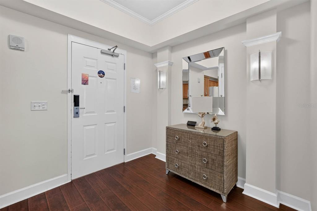 An entryway features a white door, a textured chest, a mirror, and dark wood flooring — 200 OCEAN CREST DRIVE UNIT 116, PALM COAST, FL