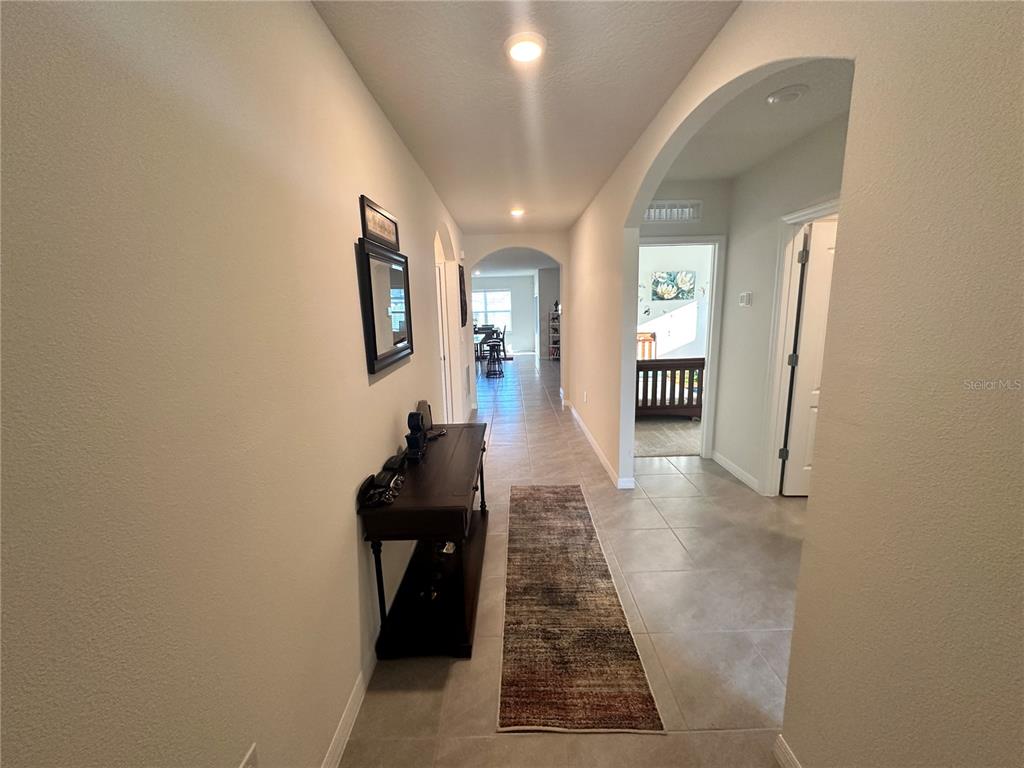 A hallway with tile flooring leads to an arched entryway and a dining area — 1855 EGRET MEADOWS AVENUE, KISSIMMEE, FL
