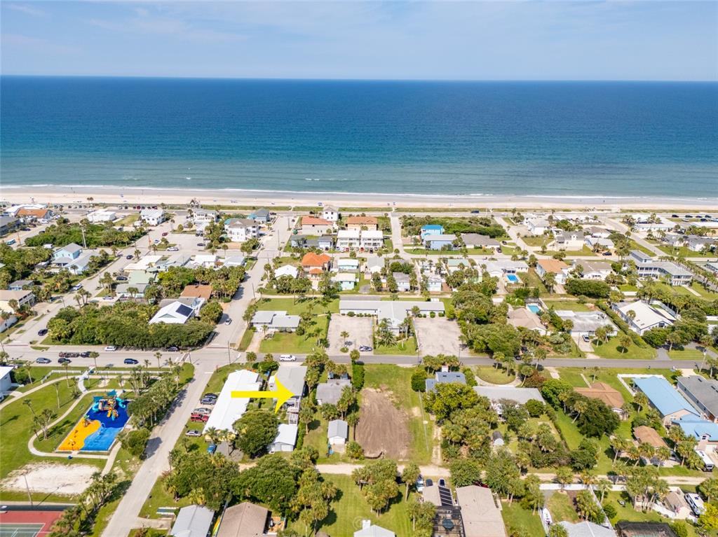 An aerial view shows a coastal neighborhood with a yellow arrow pointing to a house — 904 S DAYTONA AVENUE, FLAGLER BEACH, FL