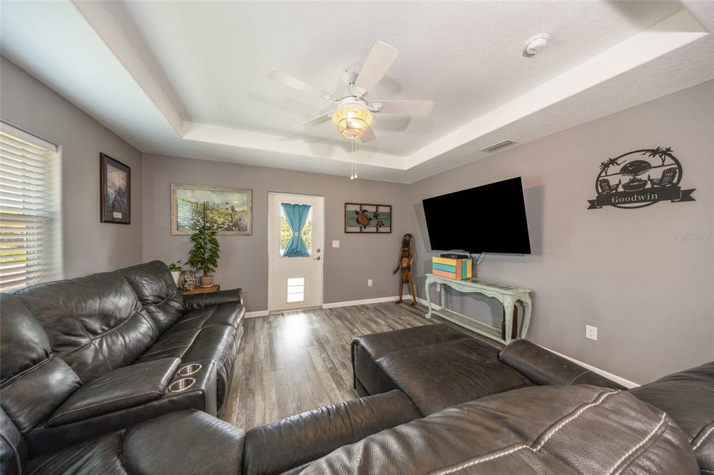 A living room features gray walls, wood-look flooring, a ceiling fan, and a sectional sofa — 904 S DAYTONA AVENUE, FLAGLER BEACH, FL
