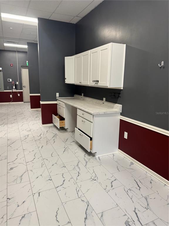 A room features white cabinets, a marble-patterned countertop, and white marble-look tile flooring — 5113 STATE ROAD 674 SUITE 108, WIMAUMA, FL