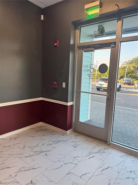 An interior view shows a tiled floor, dark walls with maroon wainscoting, and a glass door — 5113 STATE ROAD 674 SUITE 108, WIMAUMA, FL