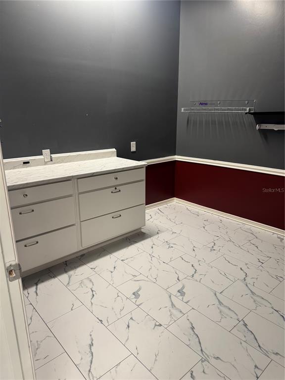 A room with white marble-patterned tile flooring, a white cabinet unit, and two-toned walls — 5113 STATE ROAD 674 SUITE 108, WIMAUMA, FL