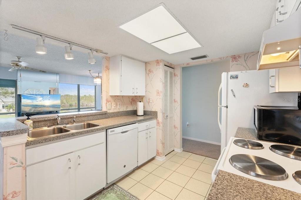 A kitchen with white cabinets, laminate countertops, a dishwasher, and a view of the outdoors — 312 108TH STREET W, BRADENTON, FL