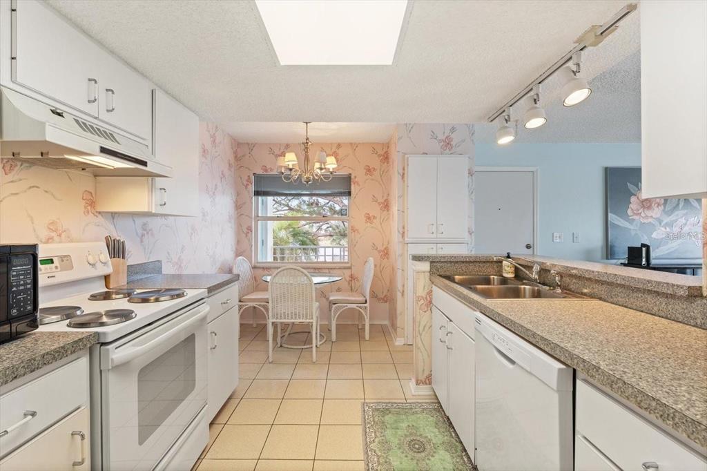 A kitchen with white cabinets, floral wallpaper, a dining nook, and a breakfast bar — 312 108TH STREET W, BRADENTON, FL