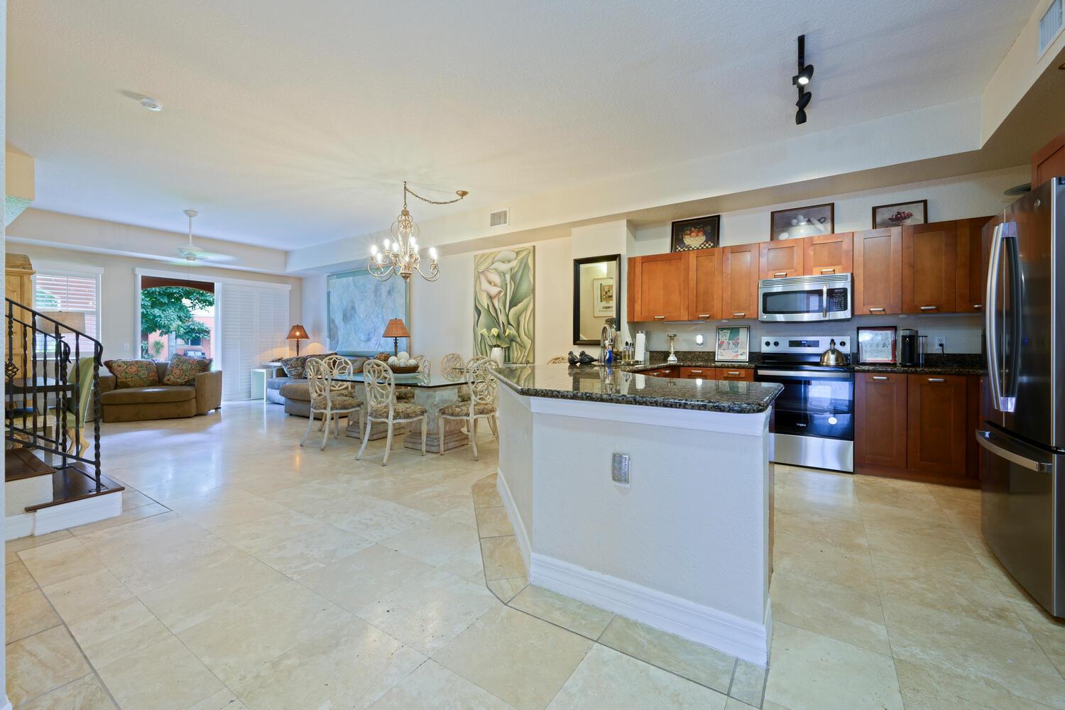 An open-concept kitchen and dining area features tile flooring, wood cabinetry, and granite countertops — 40 SE Sedona Circle # 103, Stuart FL 34994, STUART, FL