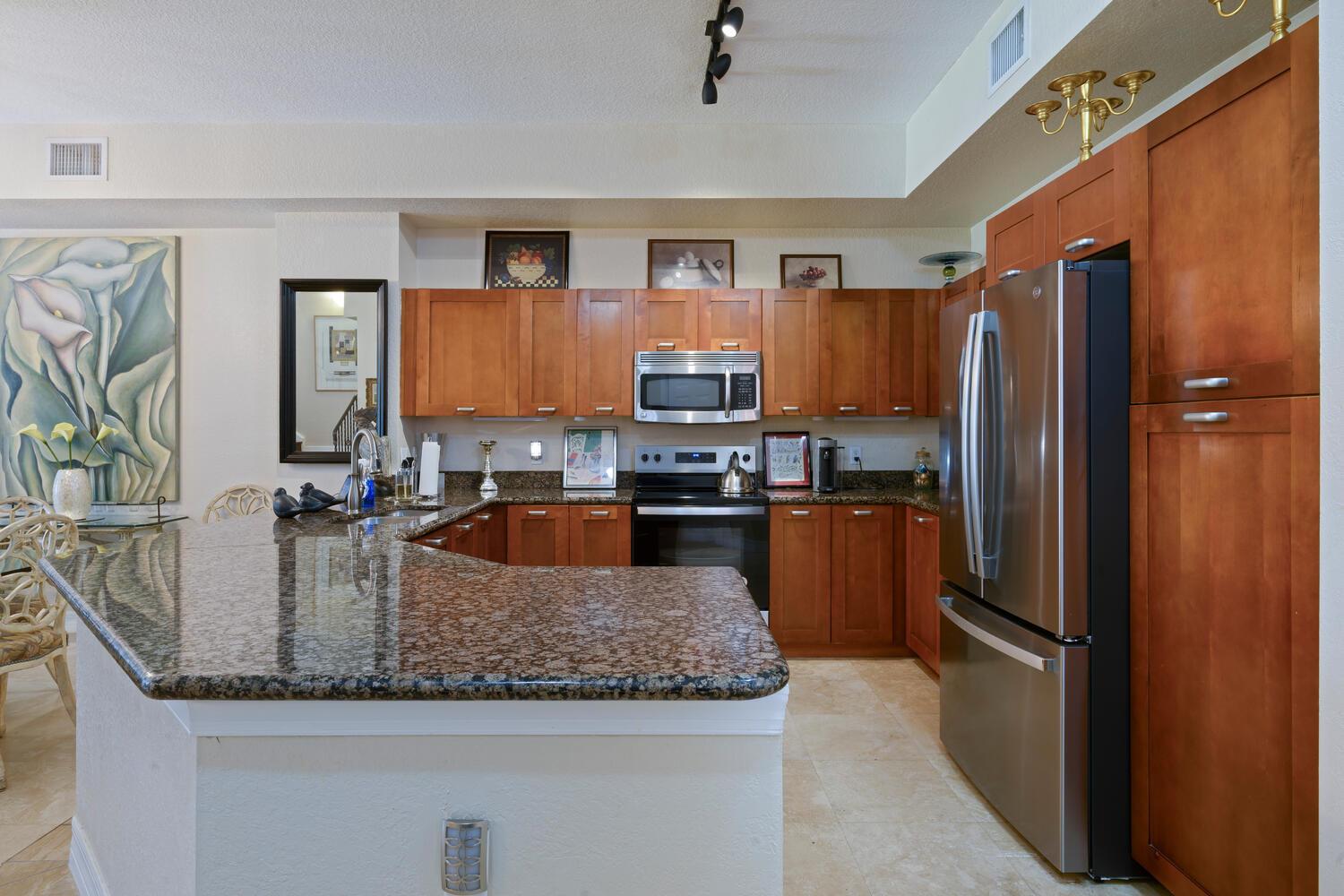 A kitchen features wood cabinets, granite countertops, stainless steel appliances, and a breakfast bar — 40 SE Sedona Circle # 103, Stuart FL 34994, STUART, FL