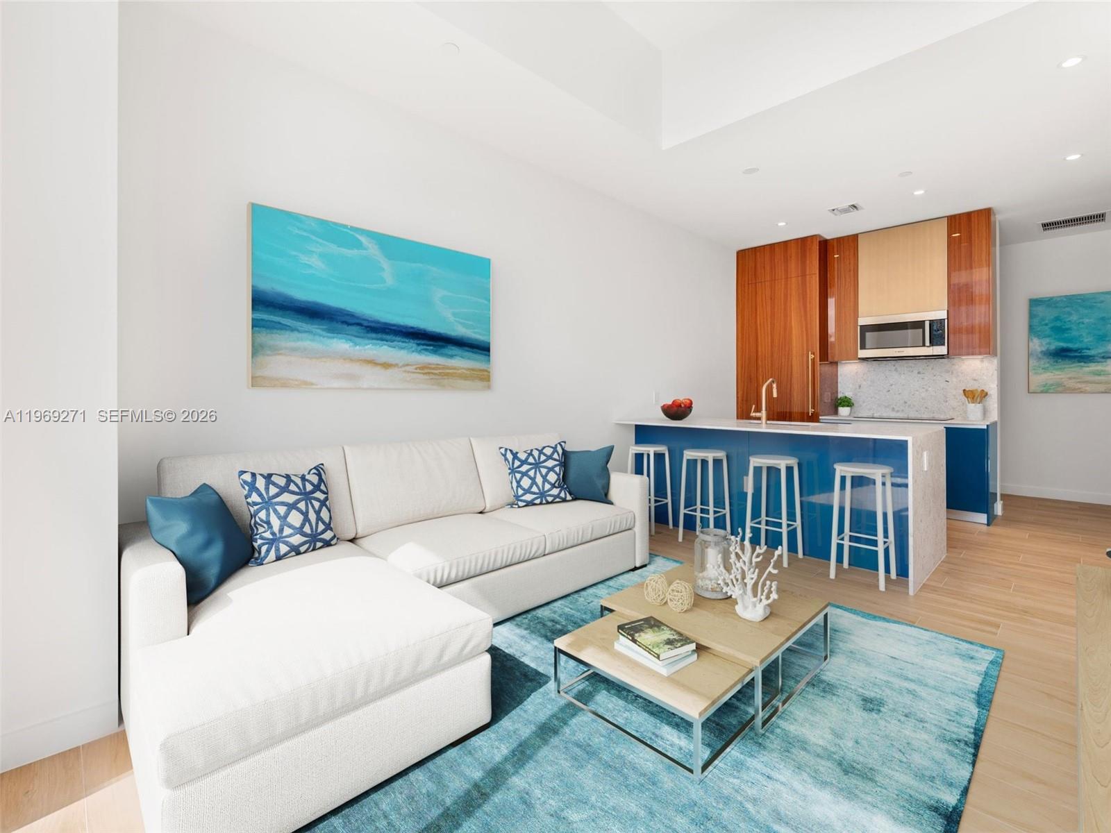 This living room and kitchen area features a white sectional sofa and blue accents — 2655 S Bayshore Dr # 1707, Miami FL 33133, MIAMI, FL