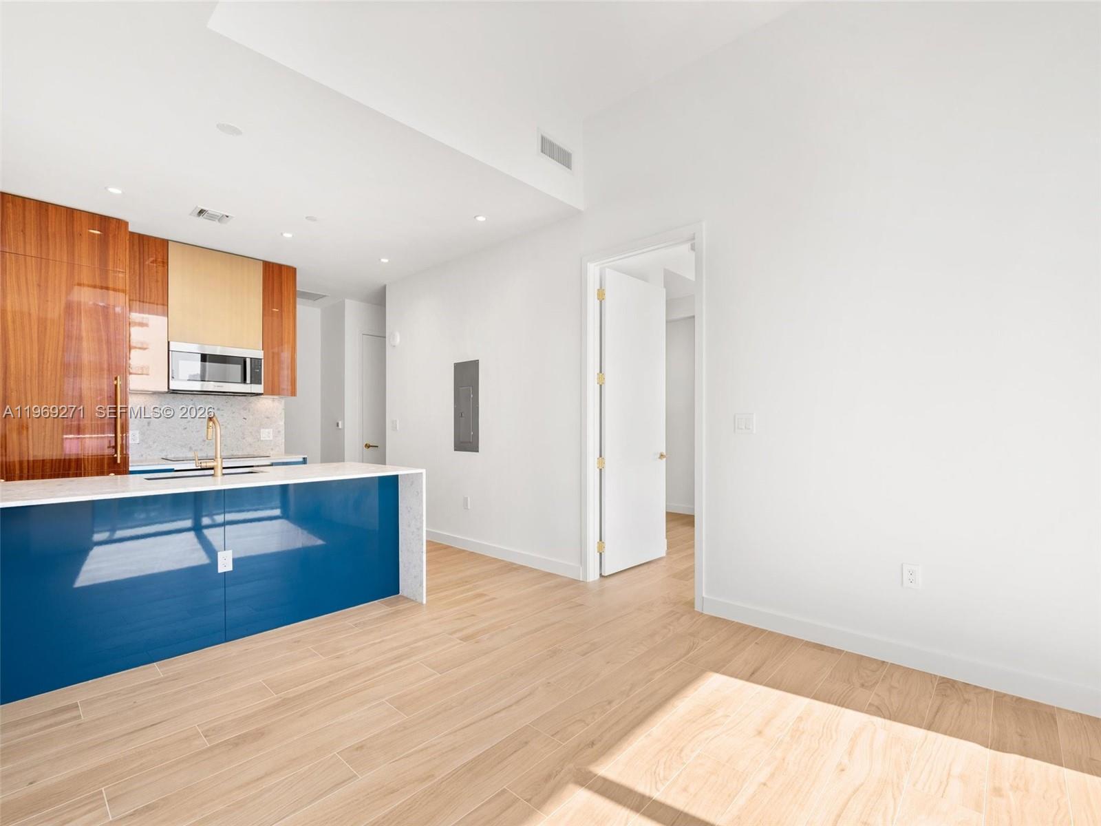 A modern kitchen features a blue island, wood-grain cabinets, and light-colored wood flooring — 2655 S Bayshore Dr # 1707, Miami FL 33133, MIAMI, FL