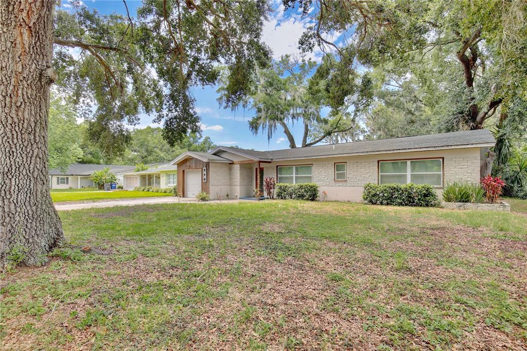 A single-story house with a stone facade, attached garage, and large trees in the yard — 2401 ALBERT LEE PARKWAY, WINTER PARK, FL