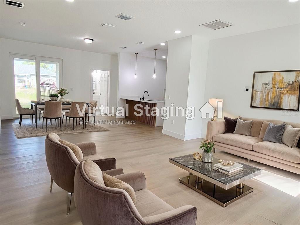 This open-concept living and dining area features light wood floors and a modern kitchen — 1751 NANDINA COURT NW, PALM BAY, FL