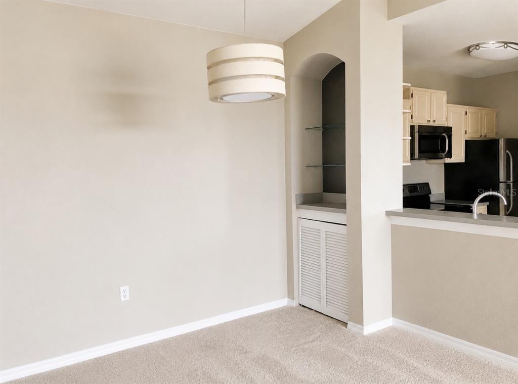 A dining area with beige carpet, a pendant light, and a built-in arched display niche — 1420 LAKE SHADOW CIRCLE UNIT 9306, MAITLAND, FL