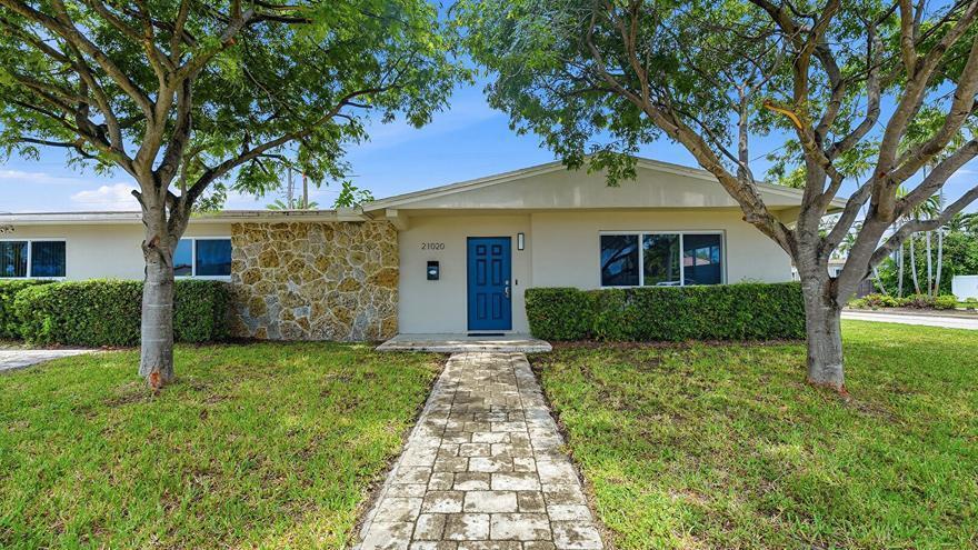 A single-story house features a blue front door, stone facade, and a stone walkway — 21020 Highland Lakes Boulevard, Miami FL 33179, MIAMI, FL