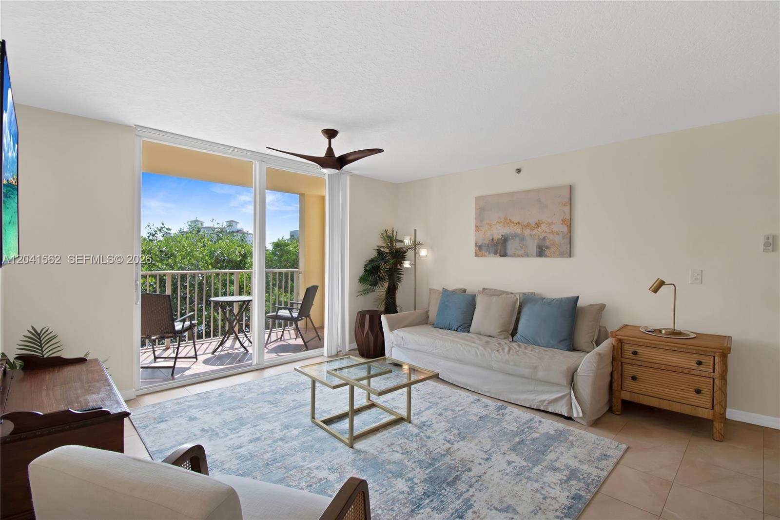 A living room features a beige sofa, glass coffee table, area rug, and balcony access — AVENTURA, FL