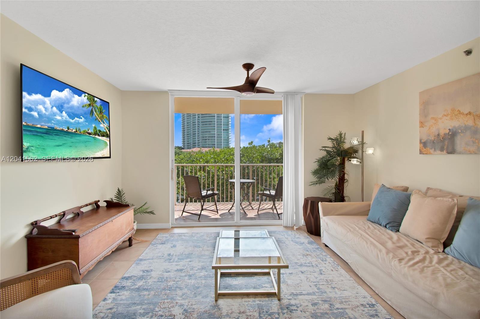 A living room features a beige sofa, a glass coffee table, and a balcony view — AVENTURA, FL