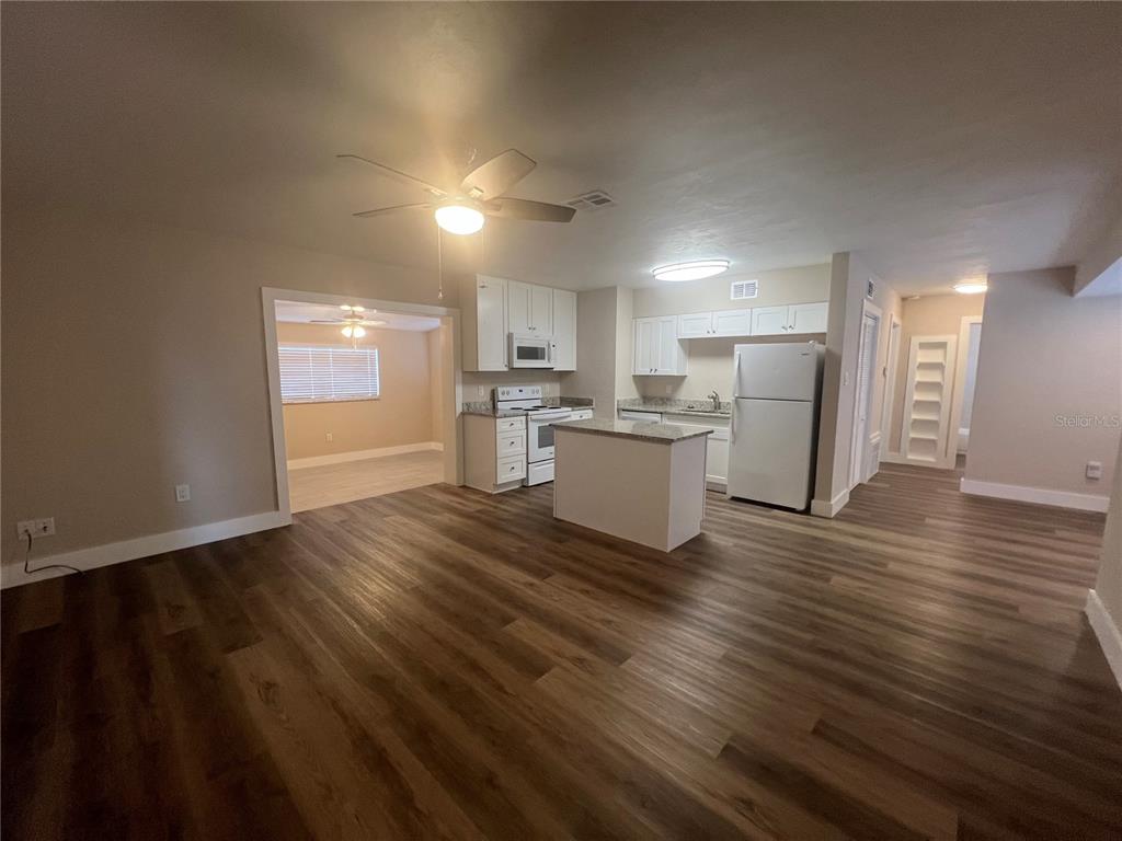 An open-concept kitchen and living area features white cabinetry, a small island, and wood-look flooring — 2472 PICNIC STREET, PORT CHARLOTTE, FL