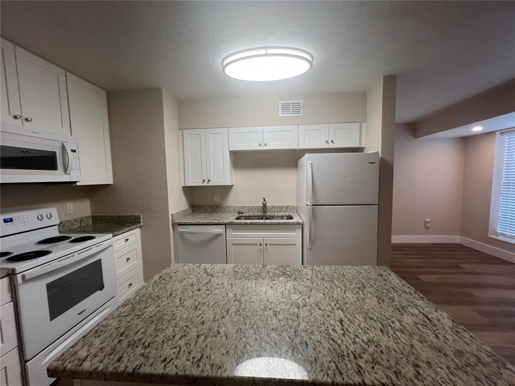 A kitchen features white cabinets, granite countertops, a white stove, and a white refrigerator — 2472 PICNIC STREET, PORT CHARLOTTE, FL
