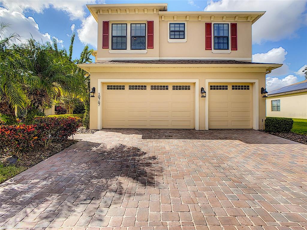 A two-story house with a beige exterior, red shutters, and a paver driveway — 10767 WILLOW RIDGE LOOP, ORLANDO, FL