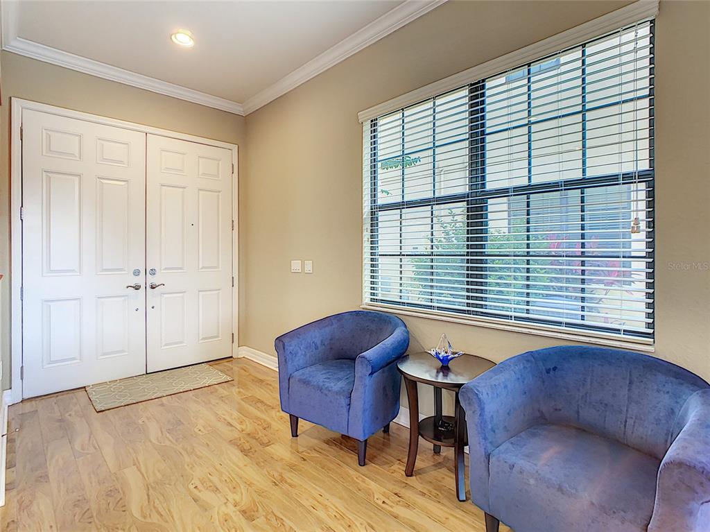A foyer with hardwood floors, two blue armchairs, a small side table, and double doors — 10767 WILLOW RIDGE LOOP, ORLANDO, FL