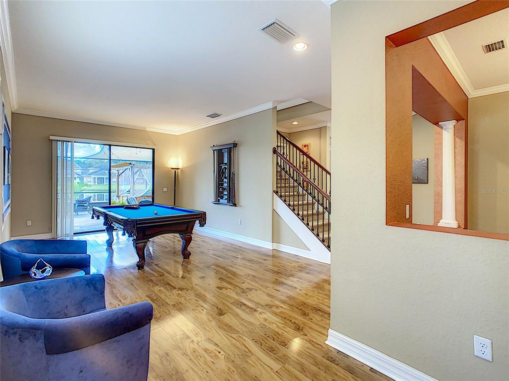 A game room features a pool table, blue armchairs, hardwood floors, and a staircase — 10767 WILLOW RIDGE LOOP, ORLANDO, FL