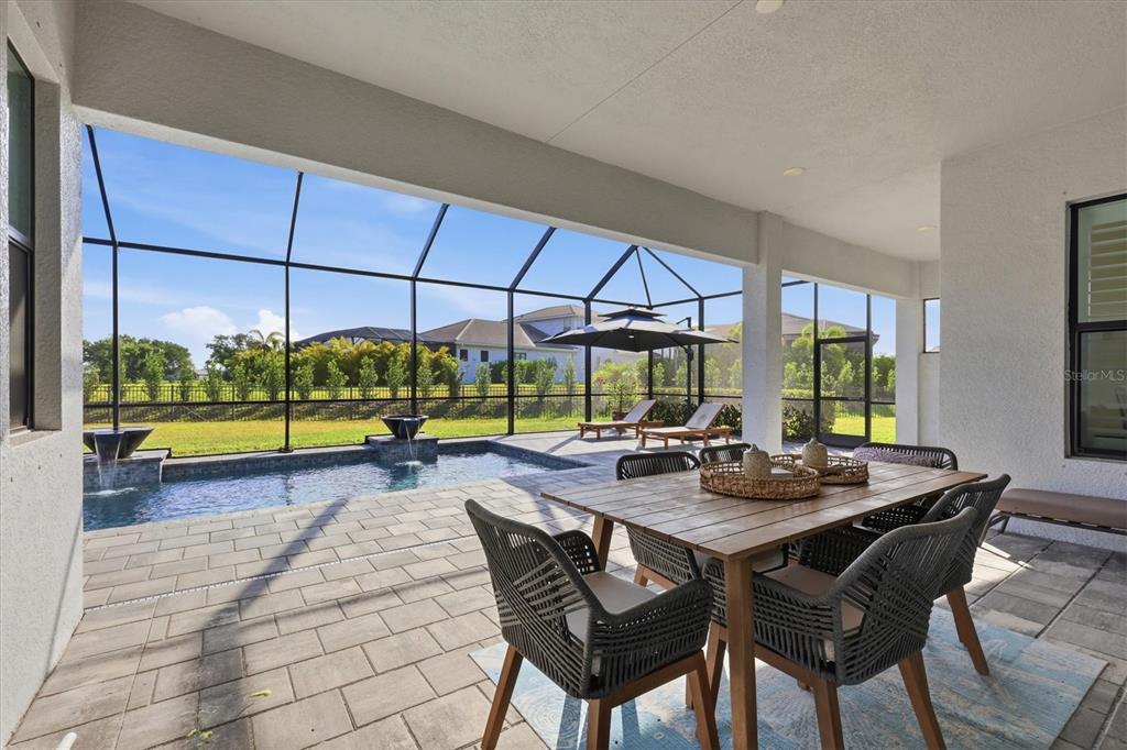 A covered patio features a dining set, a pool with fountains, and a screened enclosure — 4950 KIVA CIRCLE, BRADENTON, FL