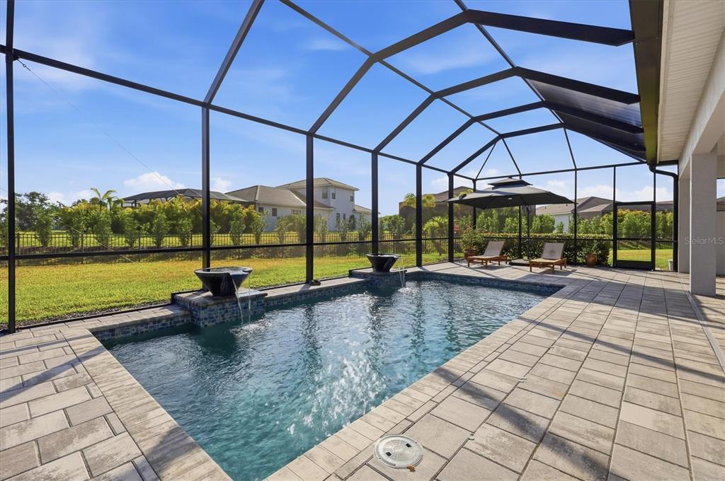 A screened-in patio features a rectangular swimming pool with two water fountains and lounge chairs — 4950 KIVA CIRCLE, BRADENTON, FL