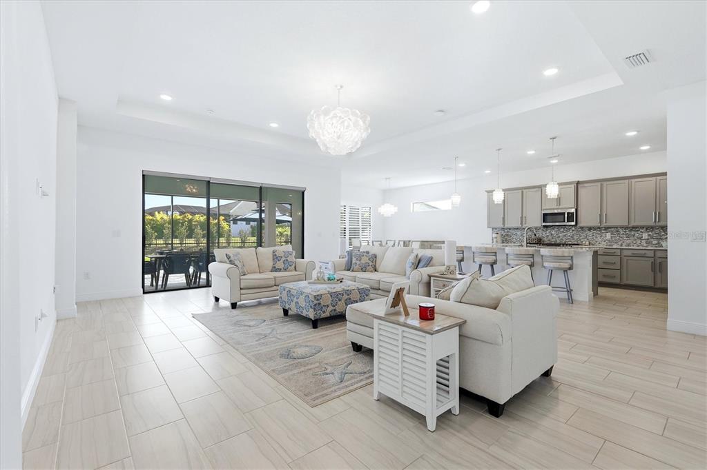 An open-concept living room and kitchen with light tile floors and neutral furniture — 4950 KIVA CIRCLE, BRADENTON, FL
