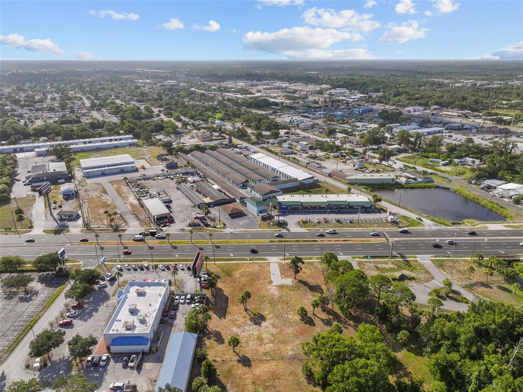 An aerial view shows a commercial plaza, parking lots, and a pond near a highway — 8807 S US 19 HIGHWAY W, PORT RICHEY, FL