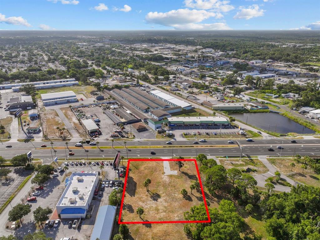 An aerial view shows a vacant rectangular lot outlined in red next to a commercial building — 8807 S US 19 HIGHWAY W, PORT RICHEY, FL