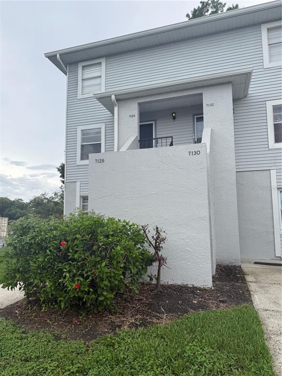 A multi-unit residential building exterior features light gray siding, a stucco entryway, and landscaping — 7128 WATERSIDE DRIVE UNIT 7128, TAMPA, FL