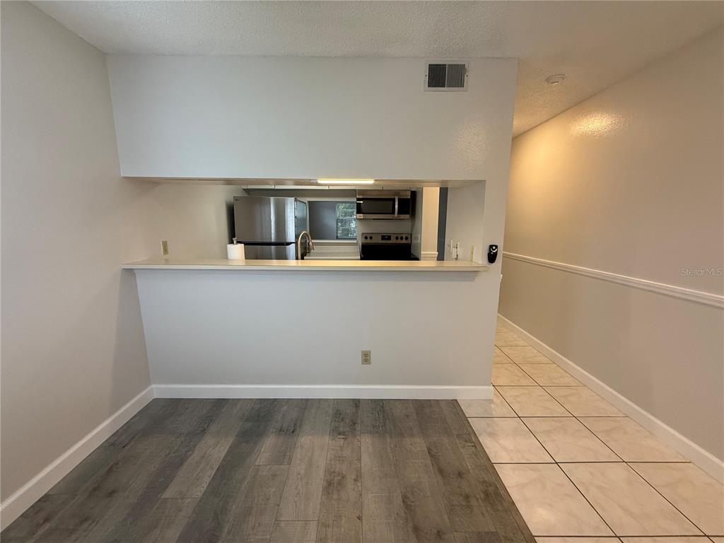 A dining area with wood-look flooring opens to a kitchen featuring stainless steel appliances — 7128 WATERSIDE DRIVE UNIT 7128, TAMPA, FL