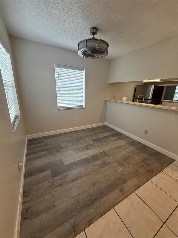 An empty room features wood-look flooring, a ceiling fan, and a pass-through to the kitchen — 7128 WATERSIDE DRIVE UNIT 7128, TAMPA, FL