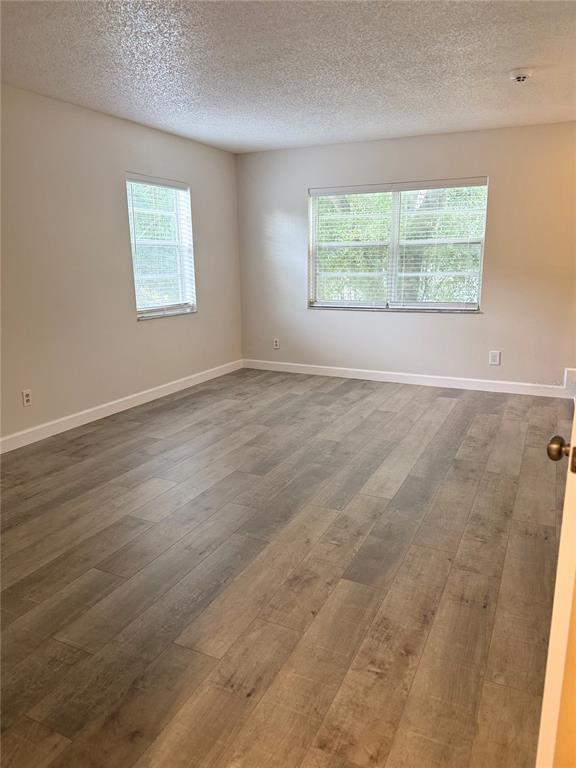 An empty room with light-colored walls, wood-look flooring, and two windows with white blinds — 7128 WATERSIDE DRIVE UNIT 7128, TAMPA, FL