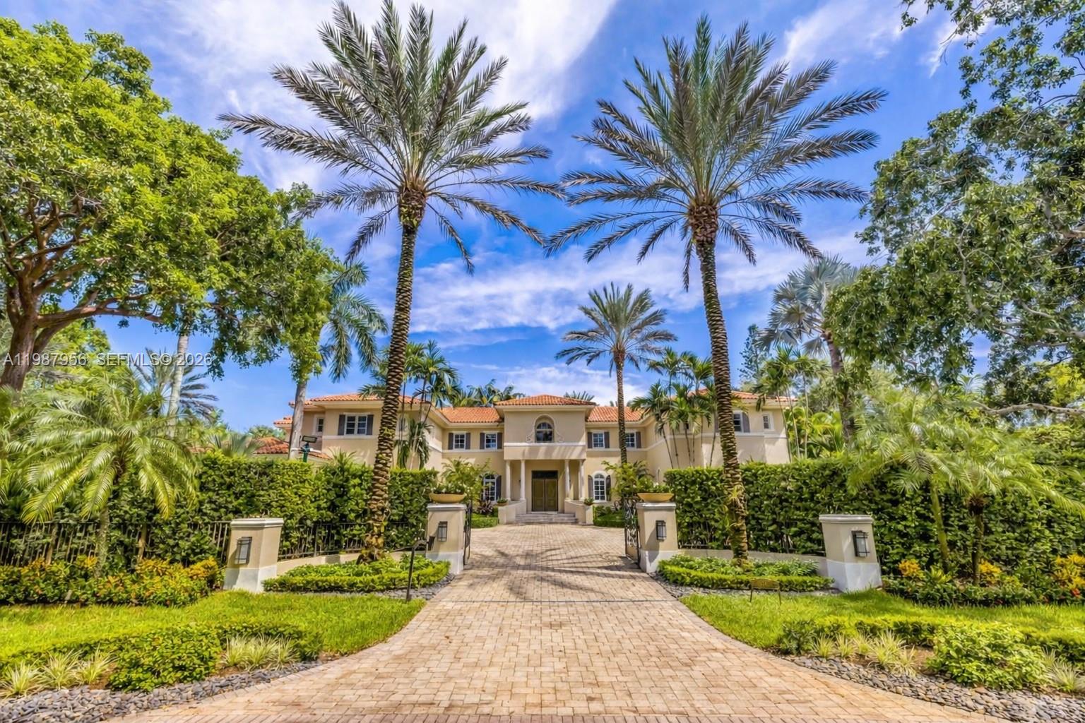 A large two-story Mediterranean-style house sits at the end of a paved driveway with palm trees — 5250 Snapper Creek Rd, Coral Gables FL 33156, CORAL GABLES, FL