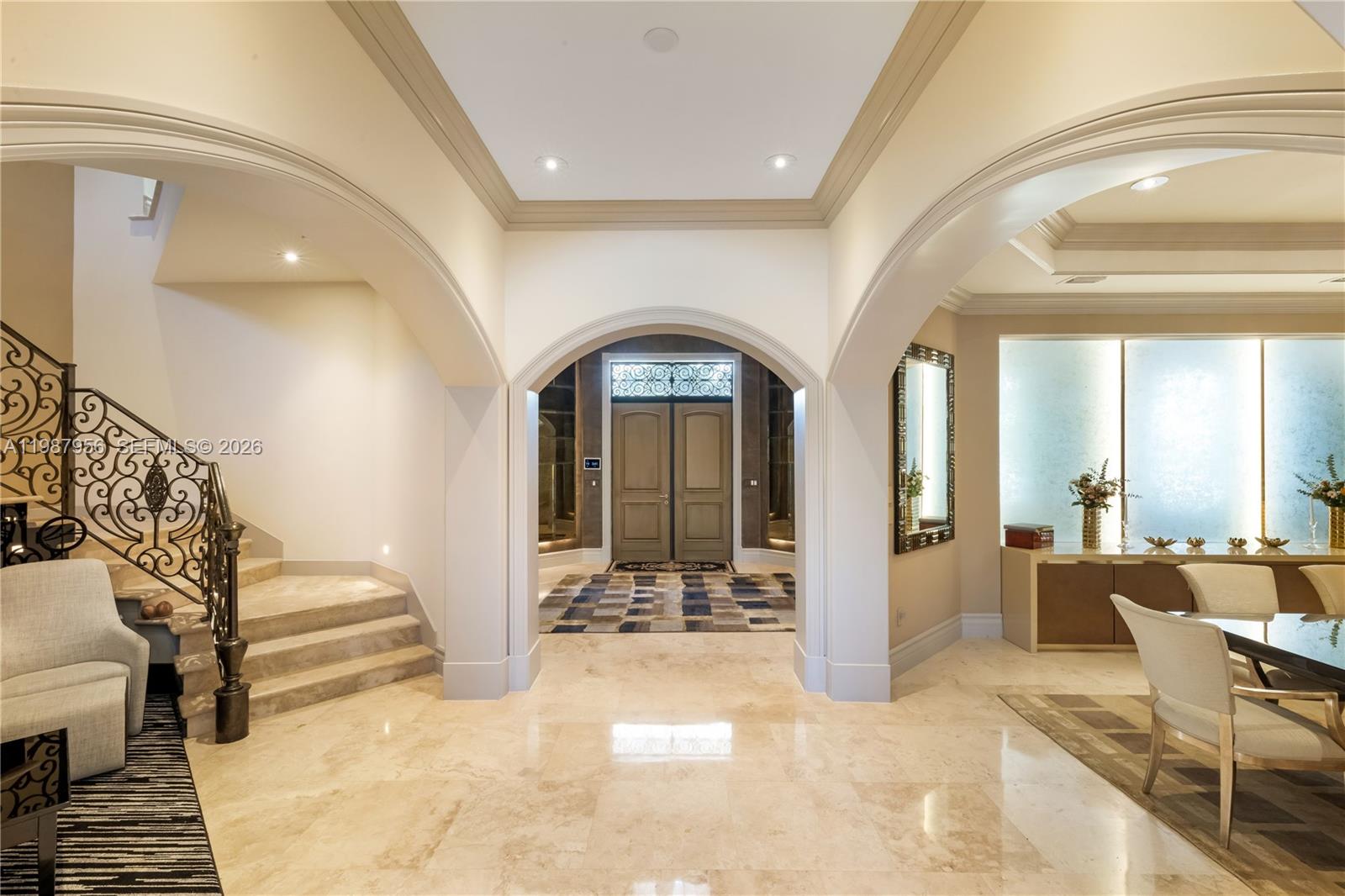 A grand foyer features arched entryways, marble flooring, and a decorative wrought iron staircase — 5250 Snapper Creek Rd, Coral Gables FL 33156, CORAL GABLES, FL