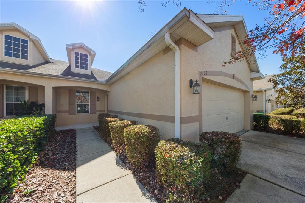 A beige stucco house with a garage, a walkway, and manicured hedges in front — 2302 BARRACUDA COURT, HOLIDAY, FL