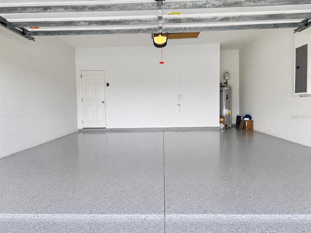 A clean, empty garage with a gray speckled epoxy floor and white block walls — 2302 BARRACUDA COURT, HOLIDAY, FL