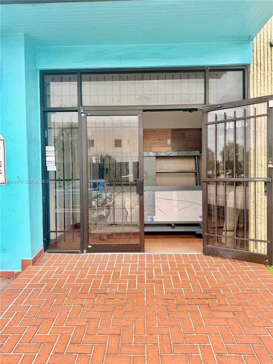 A storefront entrance features a glass door, metal security gate, and red brick flooring — 3080 SW 8th St, Miami FL 33135, MIAMI, FL