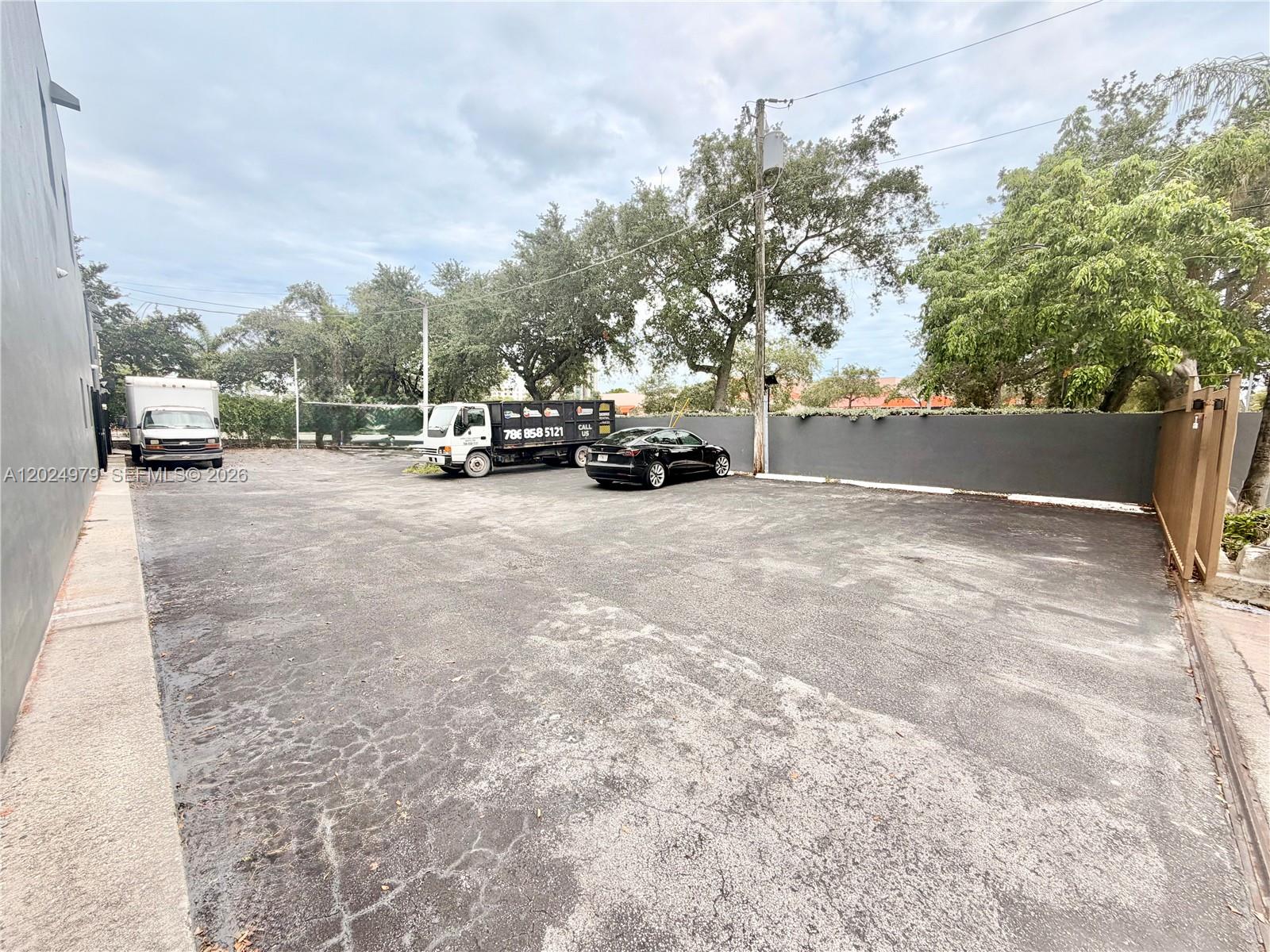 An outdoor parking lot features a paved surface, a dumpster truck, and a black car — 3080 SW 8th St, Miami FL 33135, MIAMI, FL