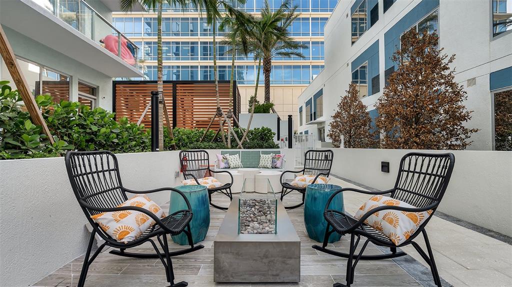 An outdoor patio features four black rocking chairs, a central fire pit, and blue side tables — 225 1ST AVENUE N UNIT B2, ST PETERSBURG, FL