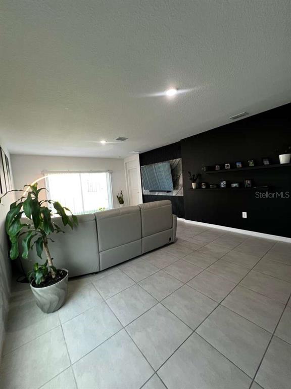A living room features a gray sectional sofa, a black accent wall, and tiled floors — 205 ACORN ROAD, HAINES CITY, FL