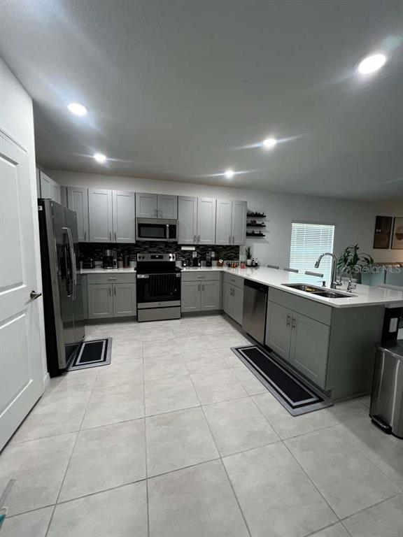 A modern kitchen features light gray cabinets, stainless steel appliances, and a large center island — 205 ACORN ROAD, HAINES CITY, FL