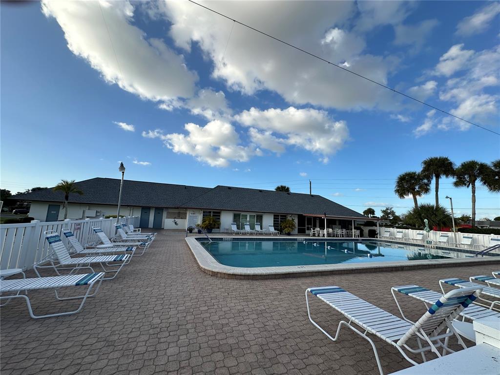 A swimming pool with lounge chairs on a brick patio in front of a building — 3401 36TH STREET W UNIT 3401, BRADENTON, FL