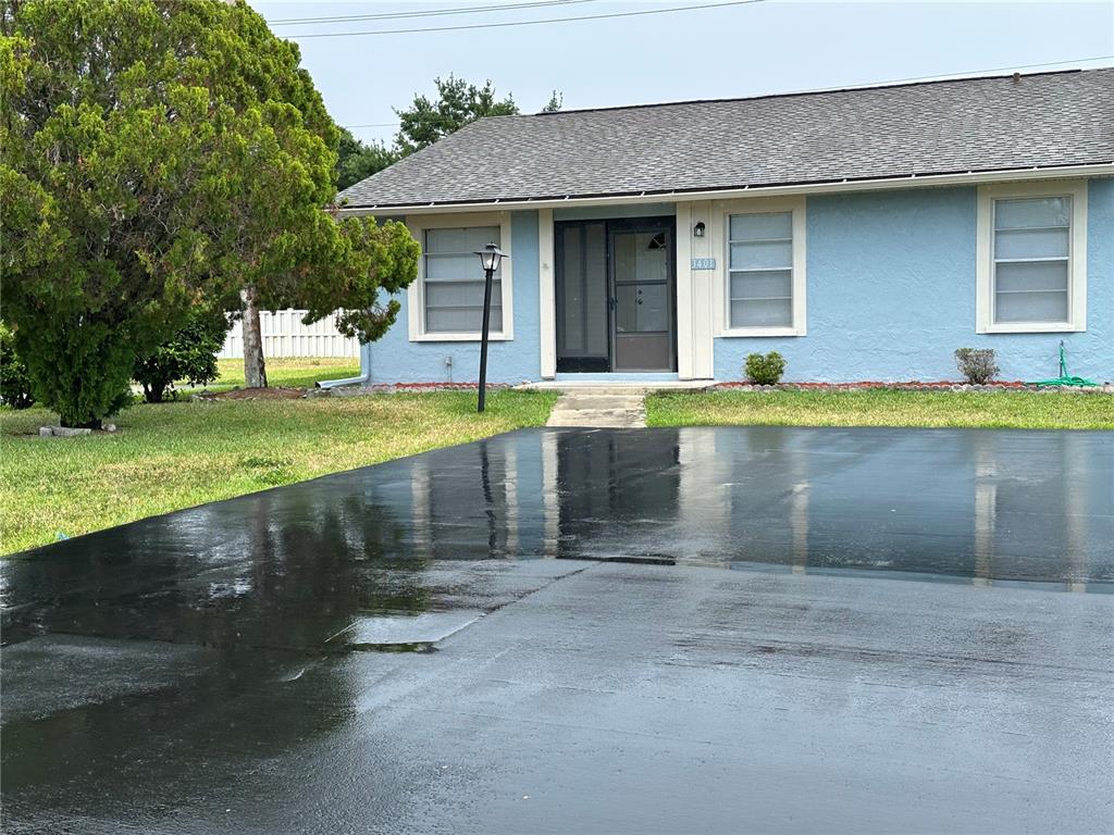 A light blue house with a dark roof and a freshly sealed black asphalt driveway — 3401 36TH STREET W UNIT 3401, BRADENTON, FL