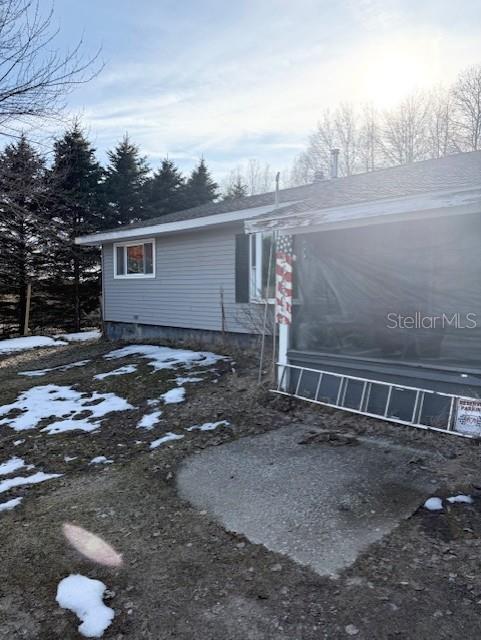 The exterior of a gray-sided house features a screened-in porch and a small concrete patio — 5297 N HUGHES AVENUE, FOUNTAIN, MI