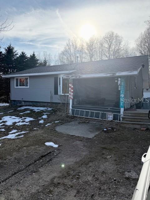 A grey-sided house with a screened-in porch and a partially snow-covered yard — 5297 N HUGHES AVENUE, FOUNTAIN, MI
